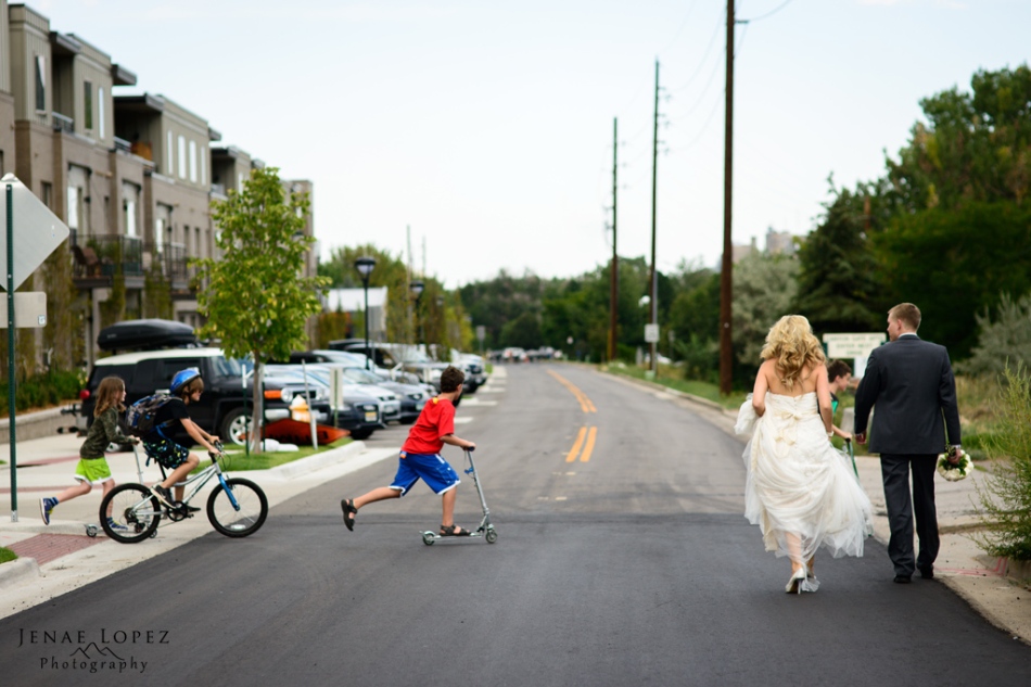 wedding environmental portrait of kids riding bikes in front of Bride and Groom walking down street