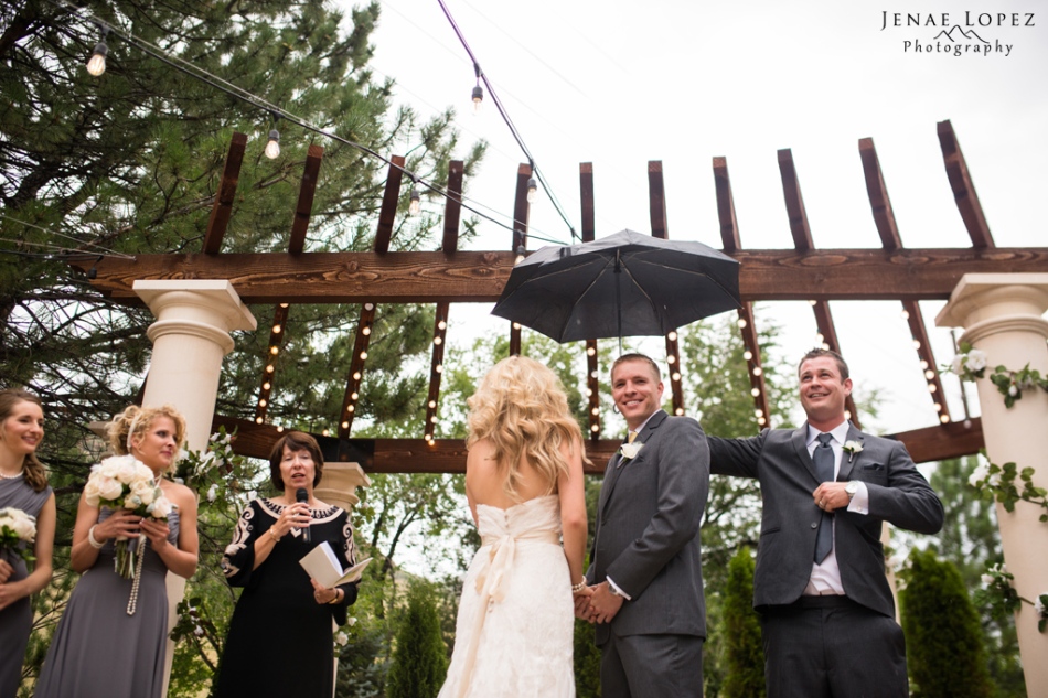 Best man holds umbrella over bride and groom during ceremony
