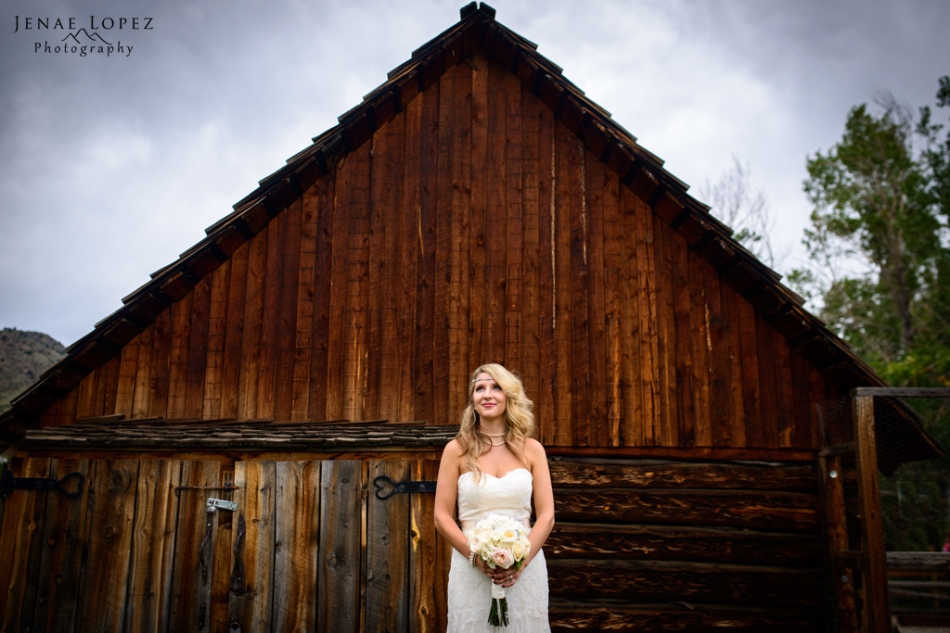 artistic photo of Bride in front of rustic barn and cloudy skies in colorado